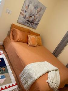 a bed with orange pillows and a painting on the wall at Warm and Comfy Antioch Cottage, close to everything in Antioch