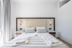 a bedroom with a large white bed with towels on it at Mythos Apartments in Damnoni