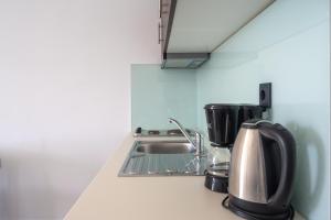 a kitchen counter with a sink and a coffee maker at Mythos Apartments in Damnoni