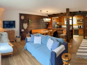 a living room with a blue couch and a kitchen at Apartment SnowKaya Grindelwald by Interhome in Grindelwald
