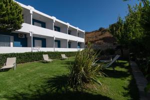 a building with chairs in the grass in front of it at Mythos Apartments in Damnoni