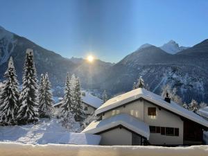 une maison recouverte de neige avec des montagnes en arrière-plan dans l'établissement Holiday Home Haus Chappali by Interhome, à Schmitten