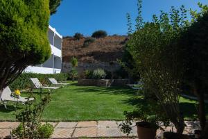 a garden with lawn chairs and a building at Mythos Apartments in Damnoni