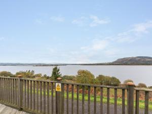 a wooden fence with a view of a lake at Chalet Loch Leven Lodge 12 by Interhome in Kinross