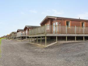 a row of wooden houses on a dirt road at Chalet Loch Leven Lodge 12 by Interhome in Kinross +32 photos