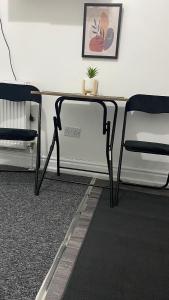 un escritorio con 2 sillas y una mesa con una planta. en BVapartments-Blackhouse F2, en Huddersfield