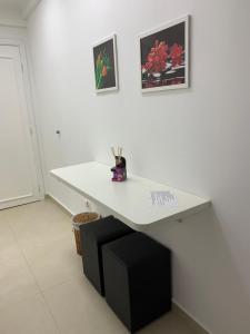 una scrivania bianca in una stanza con due foto sul muro di Hotel Cavalinho Branco - Apartamento 136 ad Águas de Lindóia