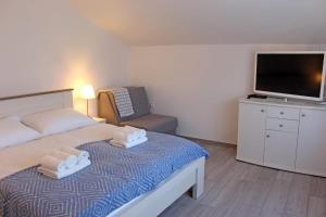 a bedroom with a bed with a television and a chair at Apartman Lavanda in Krapina