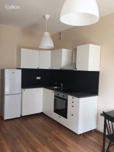 a kitchen with white cabinets and a black counter top at Žvėryno appartment-Self check-in-Free garage in Vilnius