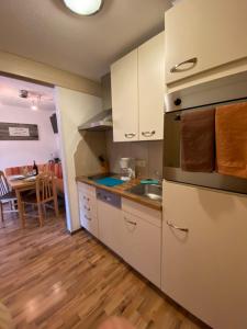 a kitchen with white cabinets and a wooden floor at Haus Evelin in Sankt Leonhard im Pitztal