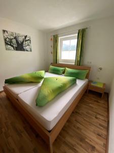 a bedroom with a large bed with green pillows at Haus Evelin in Sankt Leonhard im Pitztal