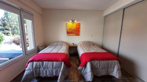 2 Betten in einem Zimmer mit Fenster in der Unterkunft Albarracin Studio in San Carlos de Bariloche