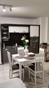 a kitchen with a white table with chairs and a vase with flowers at Apartmán Mignon in Prachatice