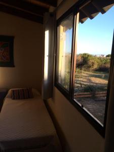 a bedroom with a window with a bed and a view at Casa Bacana in Punta Del Diablo