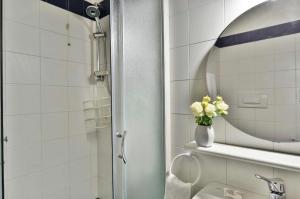 een badkamer met een spiegel en een vaas met bloemen bij Como in Milaan