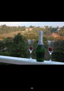 - une bouteille de vin et deux verres sur le rebord de la fenêtre dans l'établissement Chale além do horizonte, à Campos do Jordão