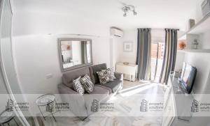 ein Wohnzimmer mit Sofa und Fernseher in der Unterkunft 1016 Piscis Apartamentos - VISTAS AL MAR - Piscina y Playa in Benalmádena