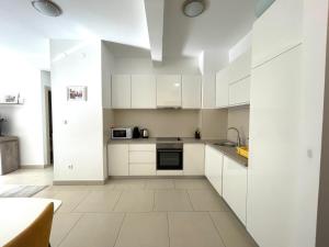 uma cozinha branca com armários e electrodomésticos brancos em Lavender Bay Lux Apartment G5 em Donji Morinj