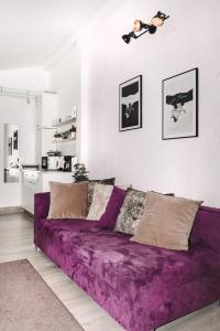 a purple couch in a living room with a kitchen at Alandala by The Center in Cluj-Napoca