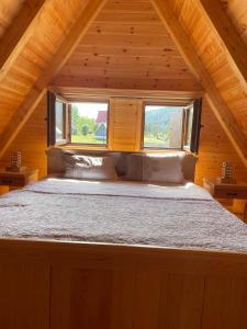 a bed in a wooden cabin with a window at Guest House LENA in Žabljak