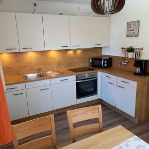 a kitchen with white cabinets and a sink at Haus Ella - Ferienhaus auf dem Land vor den Toren Salzburgs in Petting