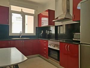 een keuken met rode kasten, een wastafel en een raam bij Maravillosa vivienda con piscina al lado del mar in La Estrella