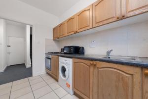 a kitchen with a sink and a washing machine at Suites by Rehoboth - Hendon Central - London in The Hyde