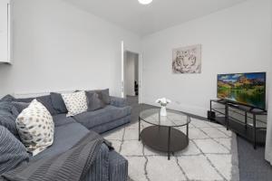 a living room with a couch and a tv at Suites by Rehoboth - Hendon Central - London in The Hyde