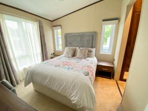 a bedroom with a bed and two windows at Wildflower, Premium Plus Hot Tub Lodge in South Cerney +36 photos