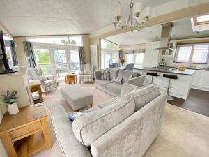 a living room with two couches and a kitchen at Wildflower, Premium Plus Hot Tub Lodge in South Cerney