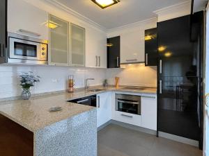 a kitchen with white cabinets and a black refrigerator at Apartamento Baztán in Elizondo