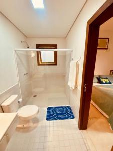a bathroom with a shower and a toilet and a bed at Pura Vida Guest House in Ilhabela