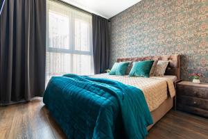 a bedroom with a bed with a blue blanket on it at Apartments on Krasnaya 176 in Krasnodar
