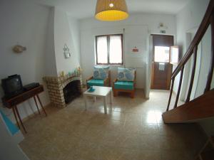 sala de estar con chimenea, sillas y TV en Ahoy Porto Covo Hostel, en Porto Covo
