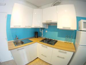 uma cozinha com armários brancos, um lavatório e um frigorífico em Ahoy Porto Covo Hostel em Porto Covo