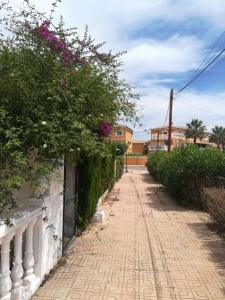 una strada di mattoni con fiori su una recinzione e un edificio di Bungalow cerca de la playa a Denia