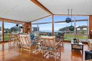 a living room with chairs and a table and windows at Matapouri Magic - Matapouri Holiday Home in Matapouri