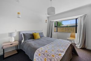 een slaapkamer met een bed en een raam bij Greytown Getaway - Greytown Holiday Home in Greytown