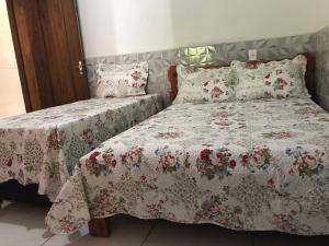 a bedroom with two beds with floral sheets and pillows at casa centro historico 5 quartos in Pirenópolis