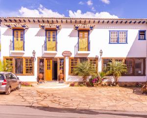 a large white building with yellow doors and windows at Pouso Tiradentes in Tiradentes