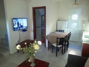 a living room with a dining room table and a television at Irini Apartments Anaxos in Anaxos