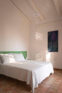 Un dormitorio con una cama blanca y una pintura en la pared en Agriturismo La Civetta, en Gioia del Colle