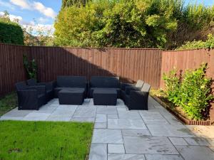 a patio with chairs and a table and a fence at Fantastic villa bournemouth - spa, parking, garden in Bournemouth