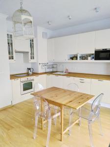 ワルシャワにあるWarsaw Concierge Vistula Apartmentの白いキャビネット、木製テーブルと椅子付きのキッチンが備わります。