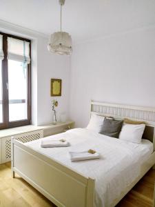 a bedroom with a large white bed with a window at Warsaw Concierge Vistula Apartment in Warsaw