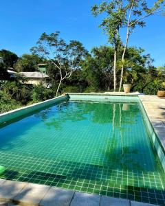 una piscina infinita con azulejos verdes en el patio trasero en Recanto da Ferradura en Búzios