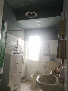 een badkamer met een wastafel, een toilet en een raam bij RaMaya, casa d'artista in Biella