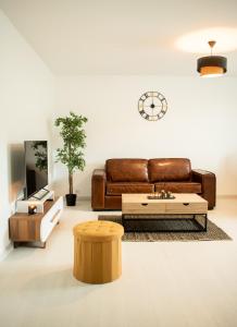 een woonkamer met een bruine leren bank en een salontafel bij Le Joyau T2-55m2 Centre ville 10min Disney in Bussy-Saint-Georges