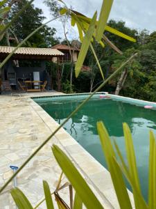 une piscine en face d'une maison avec de l'eau verte dans l'établissement Recanto da Ferradura, à Búzios