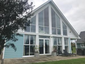 Casa azul con ventanas de cristal y patio en The Grove, en Belturbet
